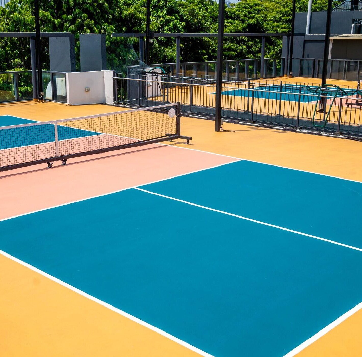 vibrant, freshly painted pickleball court features peach, yellow and blue colors and crisp lines, outdoor sports setting concept